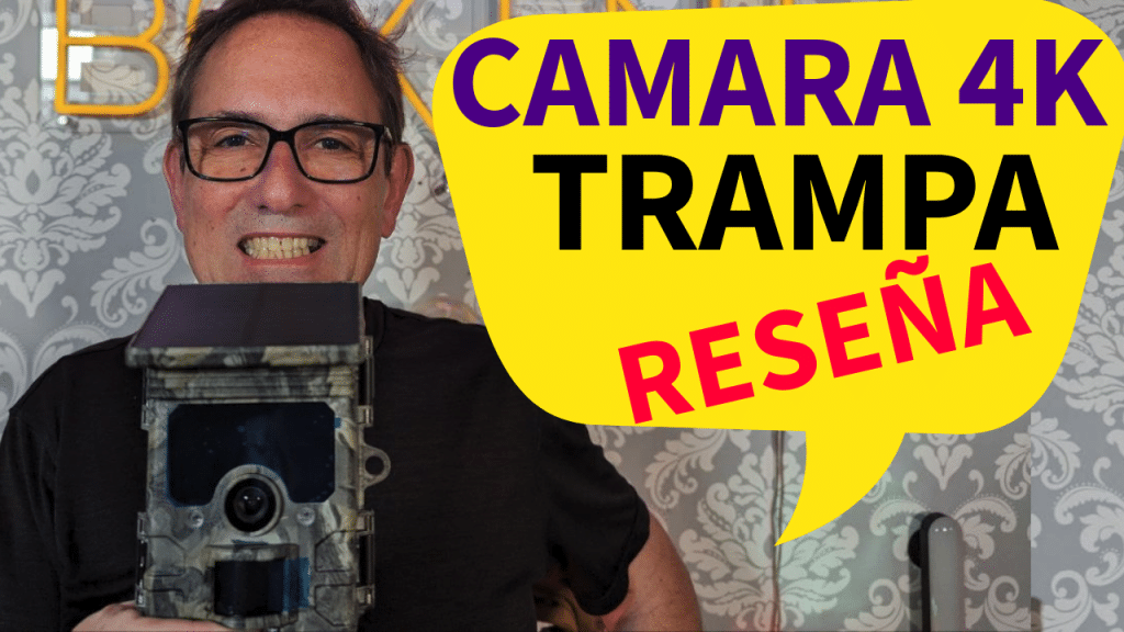 Un hombre sonriente sosteniendo una cámara de camuflaje 4K con un fondo decorativo y texto superpuesto que dice "CAMARA 4K TRAMPA RESEÑA".